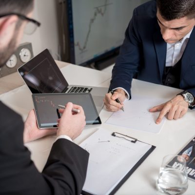 pexels-photo-7316661-7316661 Two businessmen analyzing cryptocurrency market trends using a tablet and laptop in an office.